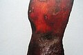 Skulptur in Braun und Rot. Leichte Form eines weiblichen Oberkörpers.
