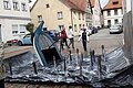 Ein gesunkenes Boot, bei welchem nur das Heck noch zu sehen ist. Rund um das Boot herum sieht man Arme aus dem Wasser ragen.