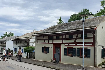 Ein Jurahaus hat am Tag des offenen Denkmals geöffnet. Eine Schar Besucher steht vor dem Haus. Das Haus ist mit Legschieferdach, Holzbalken und grünen Fensterläden ausgestattet.