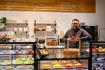 Der Besitzer des Cafe El Retiro steht hinter seiner Theke mit einer Tasse Kaffee in der Hand.